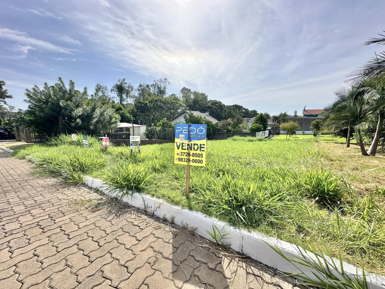 Vista da fachada de uma propriedade em Lajeado, Brasil, com área gramada e vegetação.