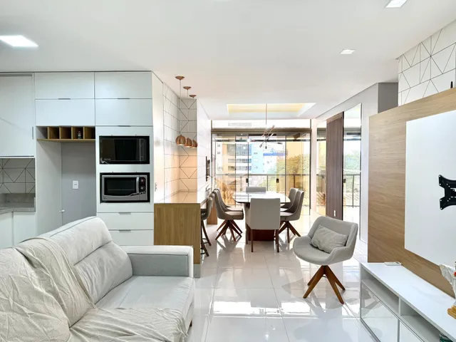 Sala de estar e jantar moderna com cozinha integrada e portas de vidro.