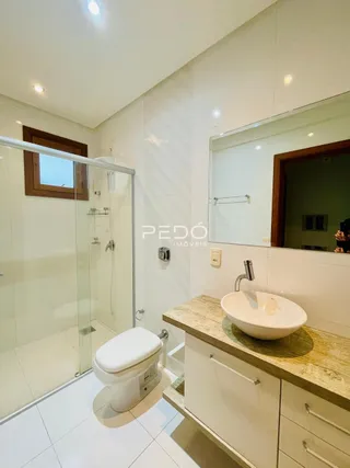 Foto de um banheiro com box de vidro e louças brancas.