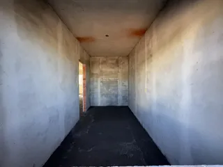 Corredor interno com paredes brancas e piso escuro.
