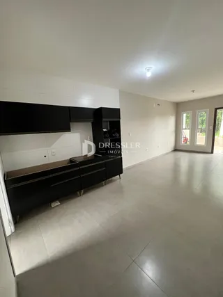Ambiente interno moderno com armários de cozinha escuros e piso claro.