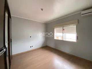 Interior de uma sala com piso de madeira e paredes cinzas.
