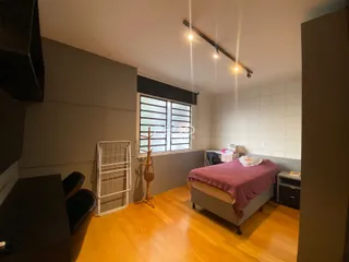 Quarto com piso de madeira e janela no interior de uma residência.