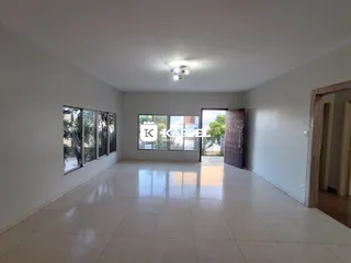 Uma sala ampla com piso de cerâmica e várias janelas.