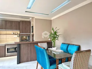 Sala de jantar com mesa de vidro e cadeiras azuis em um imóvel no Brasil.