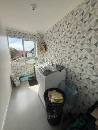 Interior de um corredor com paredes revestidas de azulejos geométricos e uma janela.