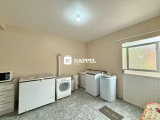 Foto interna de uma cozinha com bancadas e máquina de lavar roupa.