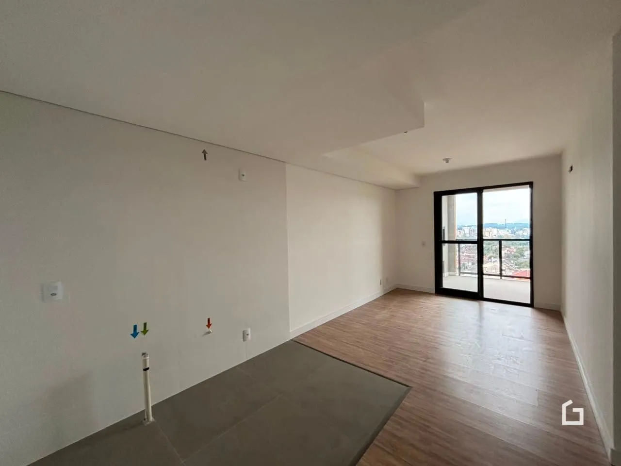 Espaço interno com piso de madeira e grande janela de vista.