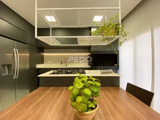 Vista da cozinha moderna com armários escuros e bancadas brancas.