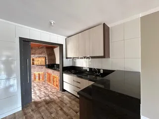 Vista interna de uma cozinha com armários e piso de cerâmica.