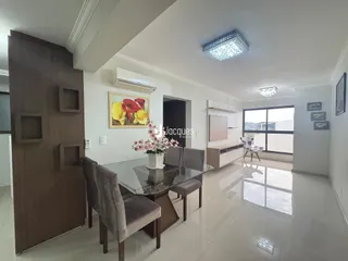 Sala de estar com mesa de jantar e grandes janelas.