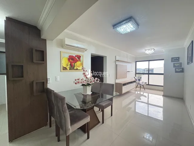 Sala de estar com mesa de jantar e grandes janelas.