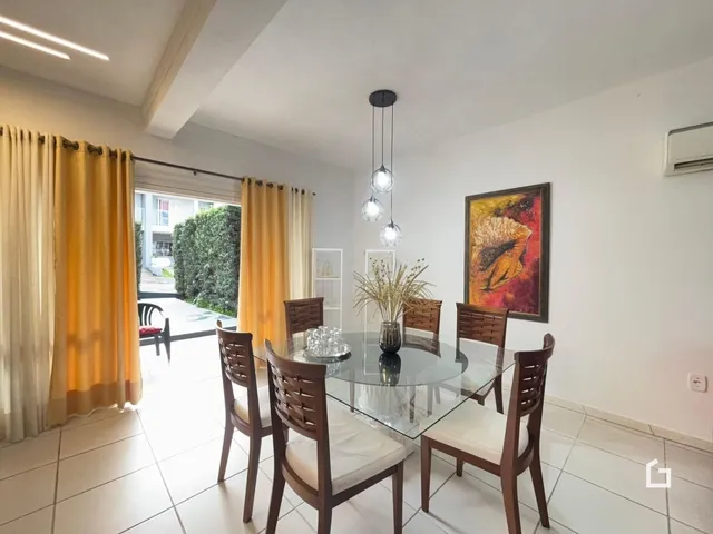 Vista de uma sala de jantar com mesa de vidro e cadeiras de madeira.