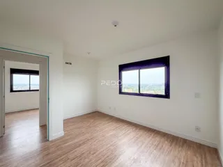 Interior de uma sala com piso de madeira e janela.