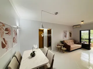 Ambiente interno de uma sala de estar com mesa de jantar e porta de entrada.