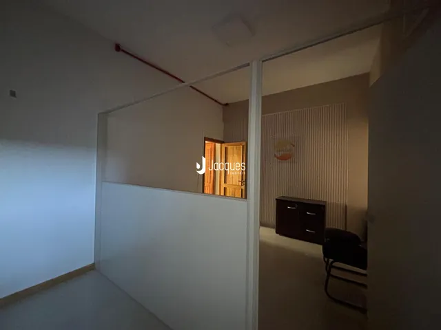 Vista de um corredor interno com paredes brancas e piso claro.