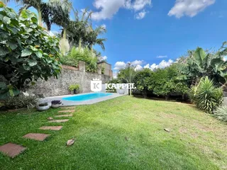 Foto externa mostrando uma piscina e um jardim com vegetação exuberante.