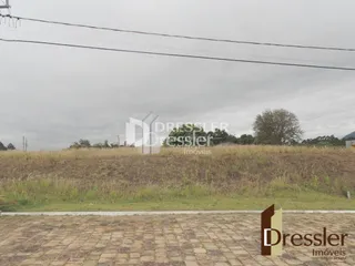 Vista de um campo gramado com árvores ao fundo.