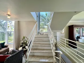Sala de estar com escadaria e vista para a vegetação externa.