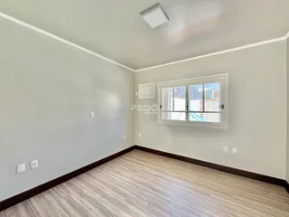 Ambiente interno de uma sala com piso de madeira clara e paredes brancas.