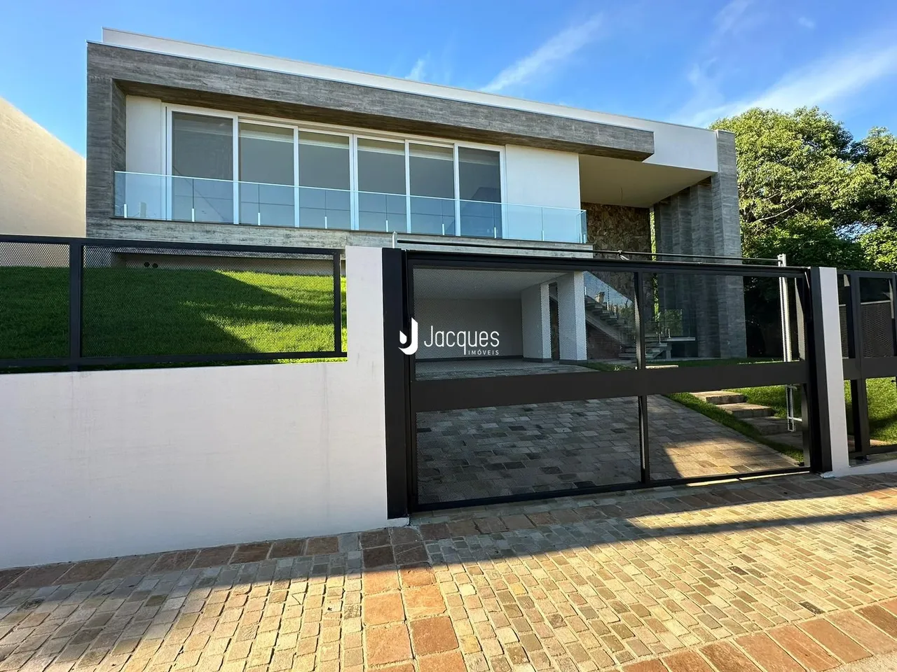 Fachada moderna de uma residência em Lajeado, Brasil, com muro e portão de ferro.