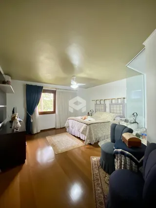 Um quarto com piso de madeira e janelas é visível na sala.