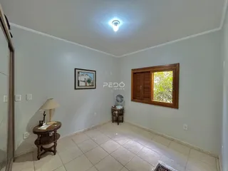 Sala de estar clara com piso de cerâmica e janela de madeira.