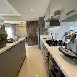 Cozinha moderna com armários brancos e bancadas claras.