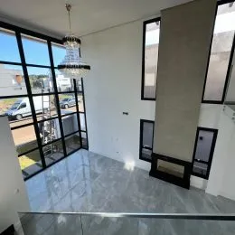 Vista externa através de grandes janelas de vidro em um ambiente interno.