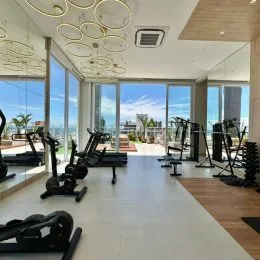 Foto de uma área de ginástica interna com equipamentos de cardio e musculação.