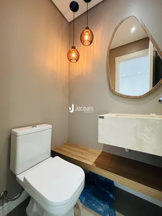 Um banheiro moderno com bancada de mármore e prateleira de madeira.