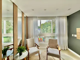 Sala de estar com janelas grandes e cortinas brancas em um imóvel no Brasil.
