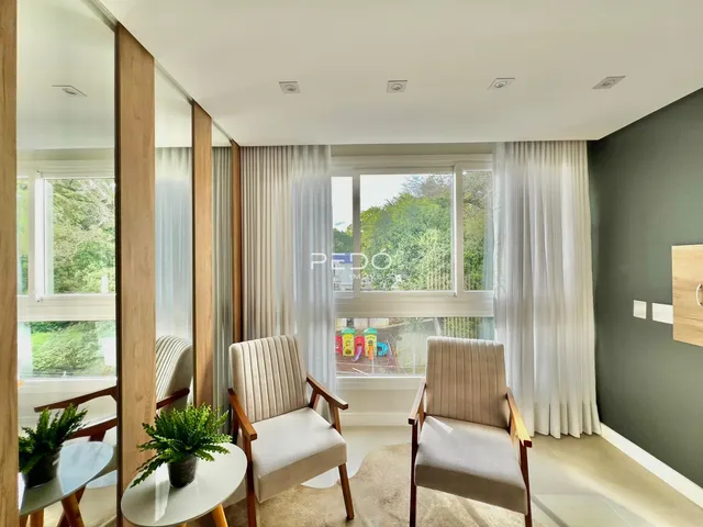 Sala de estar com janelas grandes e cortinas brancas em um imóvel no Brasil.