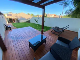 Deck de madeira com mesa de vidro e móveis externos em área externa.