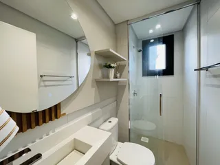 Banheiro moderno com box de vidro e revestimento claro.