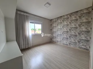 Ambiente interno de uma sala com piso de madeira clara e parede texturizada.