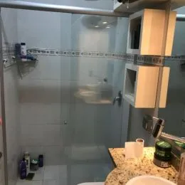 Foto de um box de banheiro com revestimento cerâmico e vidro.