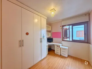 Quarto com armários embutidos e piso de madeira.