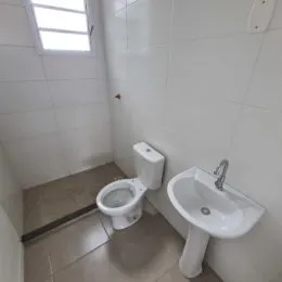 Foto interna de um banheiro com vaso sanitário e pia brancos.