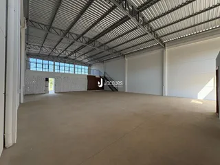 Vista interna de um grande espaço industrial com teto de estrutura metálica.