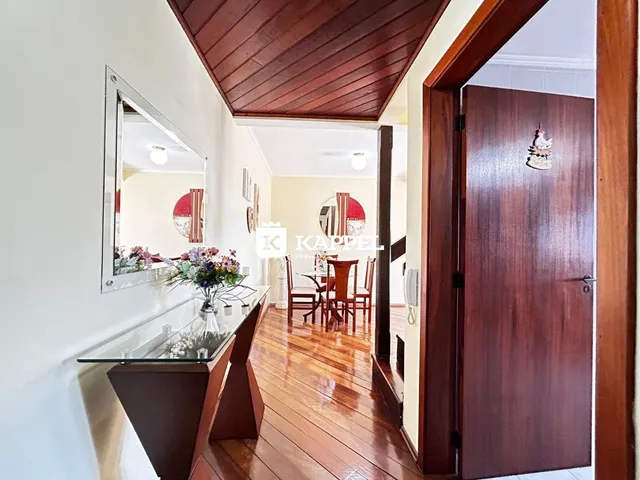 Vista de uma sala com piso de madeira e teto inclinado, mostrando um ambiente bem iluminado.