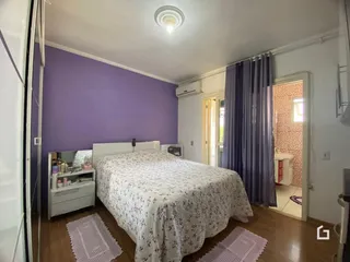 Quarto com paredes roxas e piso de madeira.