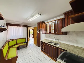 Interior da cozinha e sala de jantar com armários de madeira e piso cerâmico.