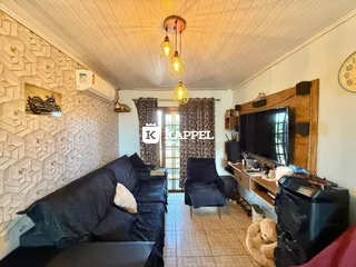 Foto interna de uma sala de estar com sofá escuro e detalhes em madeira.