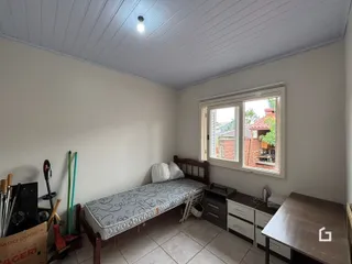 Quarto com cama de madeira e janela no interior de uma residência.