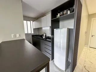 Vista da cozinha moderna com armários brancos e bancada escura.
