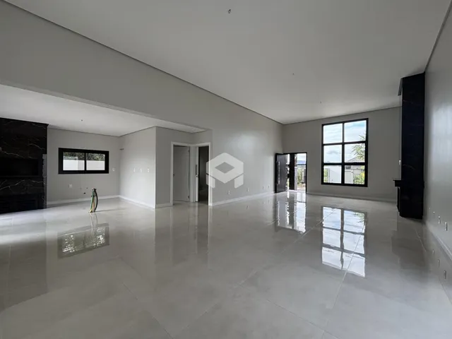 Ambiente interno amplo com piso polido e grandes janelas.