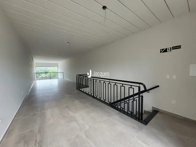 Corredor interno de uma residência com piso de cerâmica e escadaria.