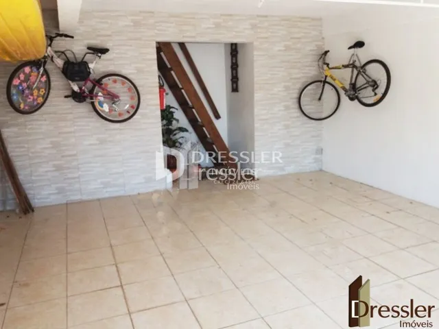 Parede branca com piso de cerâmica e bicicletas expostas em um ambiente interno.