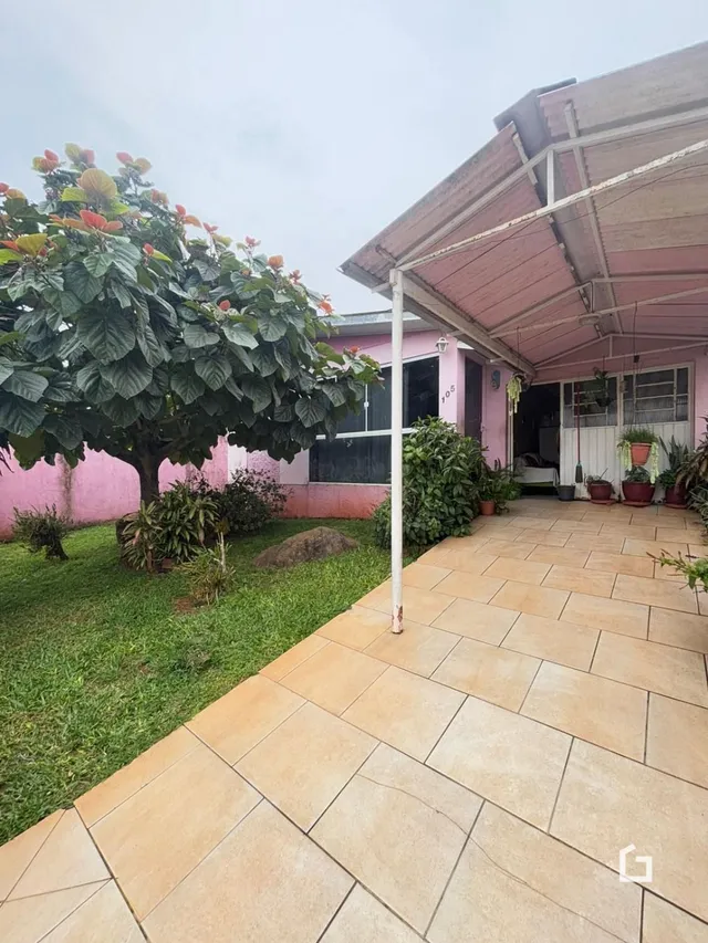 Vista da fachada de uma residência com jardim e área externa.